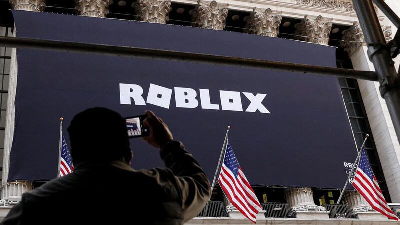 Un hombre fotografía una pancarta de Roblox colocada en la fachada de la Bolsa de Nueva York...