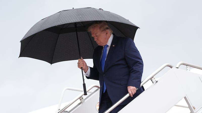 El presidente de Estados Unidos, Donald Trump, lleva un paraguas para desembarcar del Air...