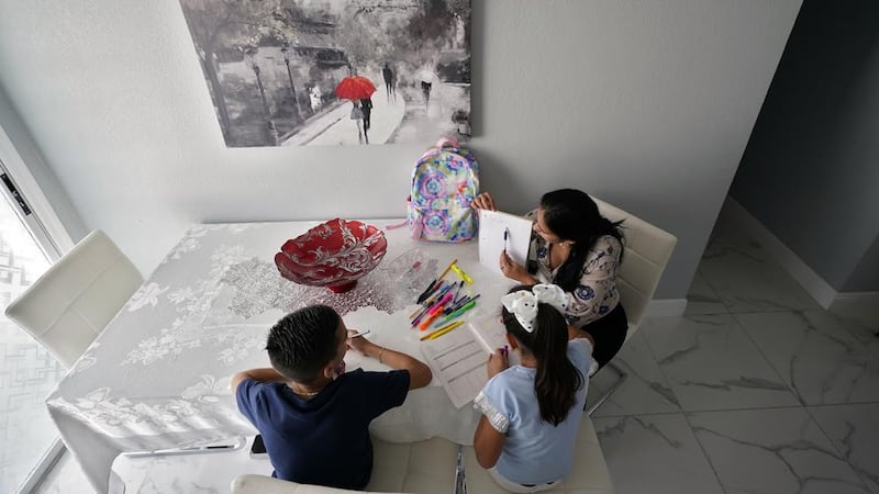 La madre de dos hijos, a la derecha, ayuda a sus hijos con la tarea en su casa el martes 19 de...
