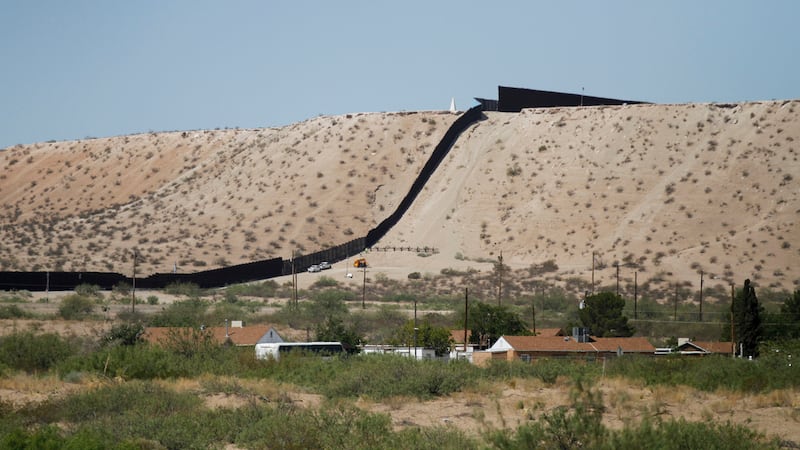 Vehículos de la Patrulla Fronteriza recorren una cerca de acero en la frontera suroeste con...