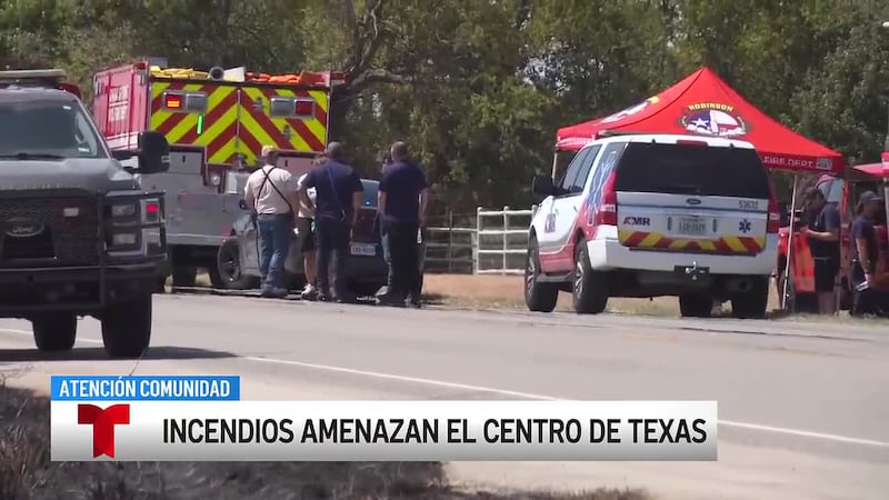 Equipos trabajan para contener un incendio de pastizales a lo largo de la línea de límite...